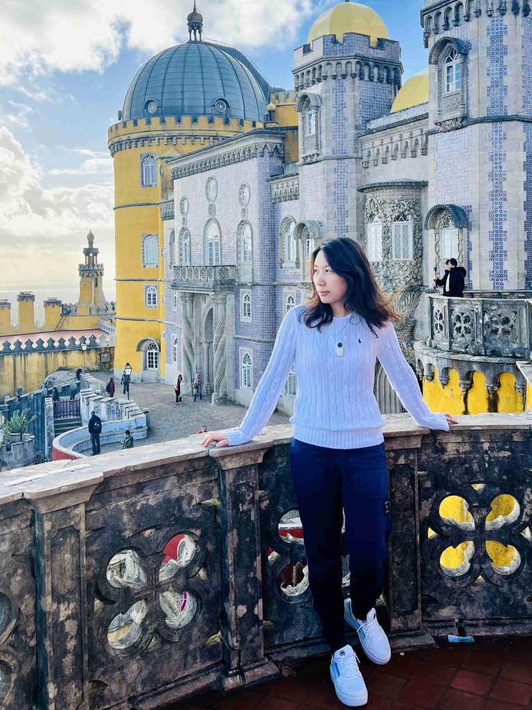 The author, Branda, posing in front of the enchanting Pena Palace during her visit to Sintra, Portugal